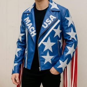 May include: A blue leather jacket with white stars and stripes, and the text "MACH USA". The jacket has a zipper closure, fringe detail, and is a bold fashion statement.