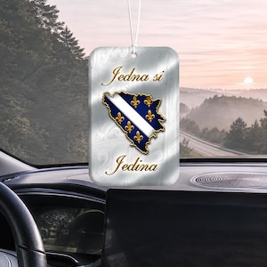 May include: A rectangular car air freshener hanging from a white string. The surface has a metallic silver finish with a swirling pattern. Centered is a map of Bosnia and Herzegovina in blue with gold fleur-de-lis and the text Jedna si Jedina.