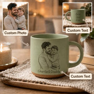 May include: A sage green ceramic mug with a brown base and handle. The mug features a custom sketch of a father and child, with the text "Charlie & Daddy" below. The mug also has the text "Best Dad Ever" on the side.