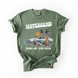 Surf lifestyle graphic tee artwork featuring classic 4x4 beach car, standing surfboard, tropical palms and rolling waves with Wavebound text.