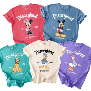 May include: A white ceramic mug with a black handle and the text "But First, Coffee" in a bold, black font. The mug is set against a blurred background, suggesting a cozy setting.