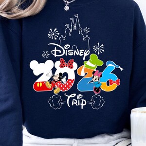 Pu&ograve; includere: Felpa blu navy con una grafica colorata Disney 2026 Trip. Il design presenta Topolino e Minnie, e una silhouette del castello. La felpa &egrave; uno stile comodo e casual.