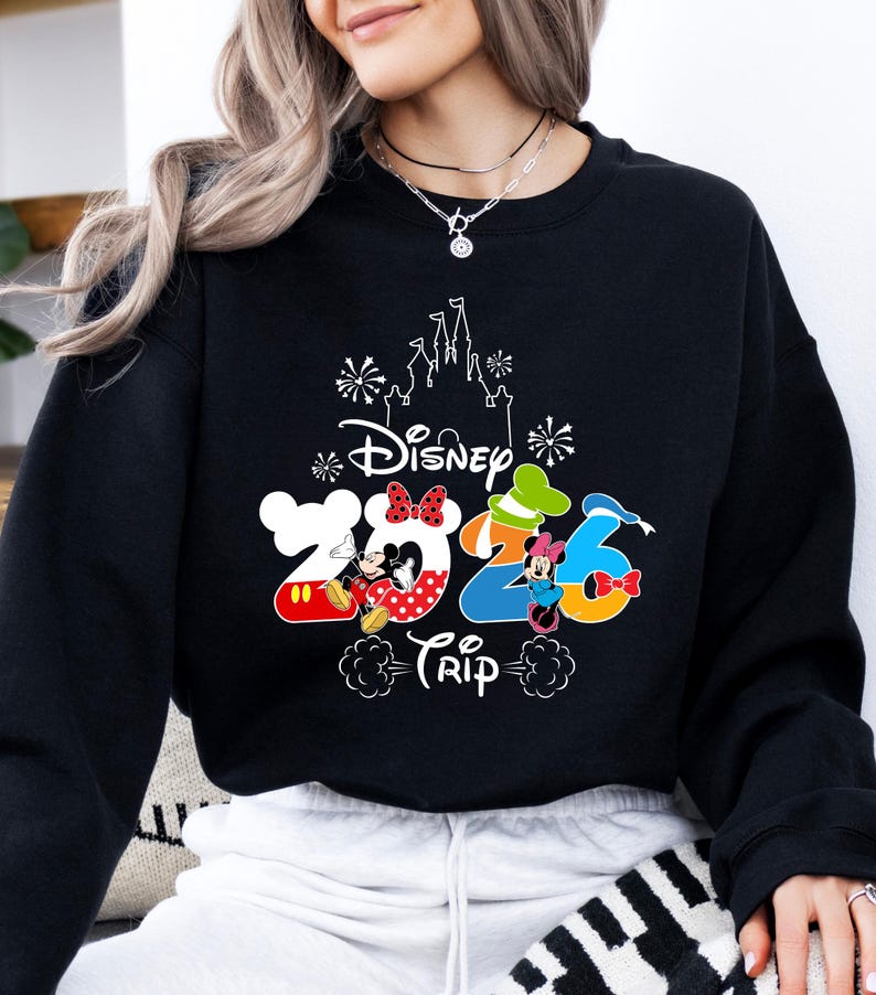 Pu&ograve; includere: Felpa nera con un design Disney colorato. Il design include il testo "Disney Trip 2026" con Topolino e Minnie, e una sagoma di castello. La felpa &egrave; uno stile girocollo.