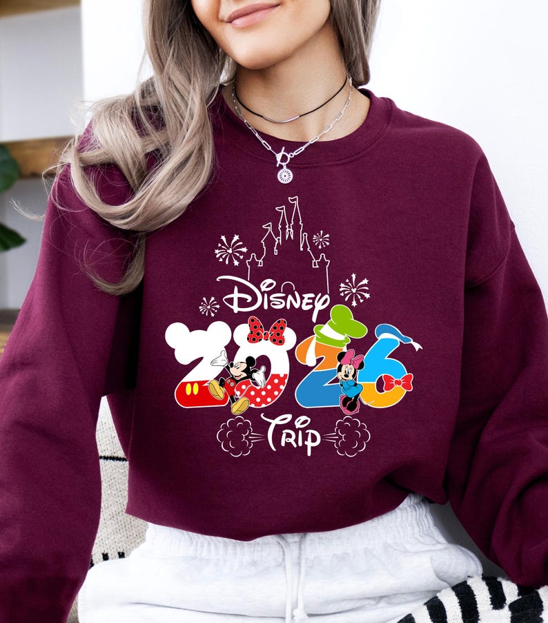 Pu&ograve; includere: Felpa bordeaux con grafica bianca del castello Disney e la scritta "Disney Trip 2026". I numeri 2026 sono disegnati con i personaggi di Topolino e Minnie. Un capo casual.