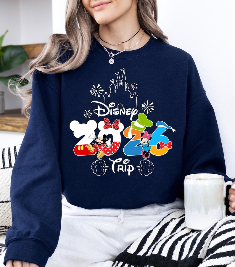 Pu&ograve; includere: Felpa blu navy con una grafica colorata Disney 2026 Trip. Il design presenta Topolino e Minnie, e una silhouette del castello. La felpa &egrave; uno stile comodo e casual.