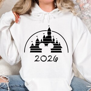 Puede incluir: Una taza de cer&aacute;mica blanca con asa negra y el texto "But First, Coffee" en negrita negra. La taza se encuentra sobre un fondo borroso, sugiriendo un ambiente acogedor.