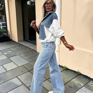 May include: A denim and white hooded jacket with matching light blue jeans and white sneakers. The jacket features a denim front and hood with white sleeves and a drawstring. The jeans are wide-legged.