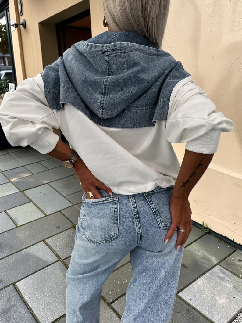 May include: A denim hooded jacket with white sleeves and light blue jeans. The jacket has a blue denim hood and a white body. The jeans are light blue and have pockets.