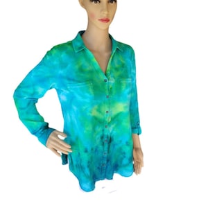 May include: A long-sleeved button-down shirt with a tie-dye pattern in shades of blue and green. The shirt has a collared neckline, two chest pockets, and buttoned cuffs. The fabric appears to be soft and lightweight.