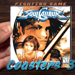 May include: A Soul Calibur 3 video game case held by a hand. The case features a colorful illustration of characters from the game, with the game's title in a stylized font. The text "FIGHTING GAME" and "Coasters 3" are also visible.