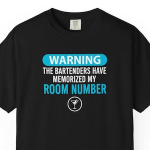 Puede incluir: Camiseta negra con el texto "WARNING THE BARTENDERS HAVE MEMORIZED MY ROOM NUMBER" en blanco y azul claro. Un icono de copa de cóctel está debajo del texto. La camiseta es de un material suave.