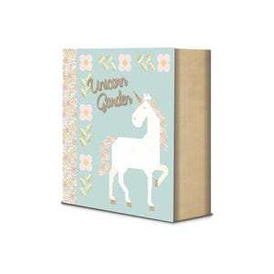 May include: A rectangular book with a light blue cover featuring a white unicorn illustration, gold glitter accents, and the text Unicorn Garden. The spine and left border display a dense floral pattern in pink, yellow, and green tones.