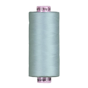 May include: A spool of light blue thread, labeled "Efilna Col" and "an Cotton 60". The thread is tightly wound around a cylindrical core. The thread's color is a soft, muted blue-green, suitable for sewing and crafting projects.