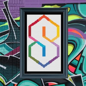 May include: Framed cross-stitch art featuring a colorful, geometric "S" design. The "S" is composed of various rainbow hues, including red, orange, yellow, green, blue, and purple. The artwork is set against a white background and framed in a dark blue frame.