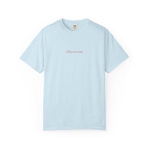 May include: A light blue t-shirt with the text "Yours truly" in a cursive font. The shirt has short sleeves and a crew neck. The fabric appears to be soft and comfortable.