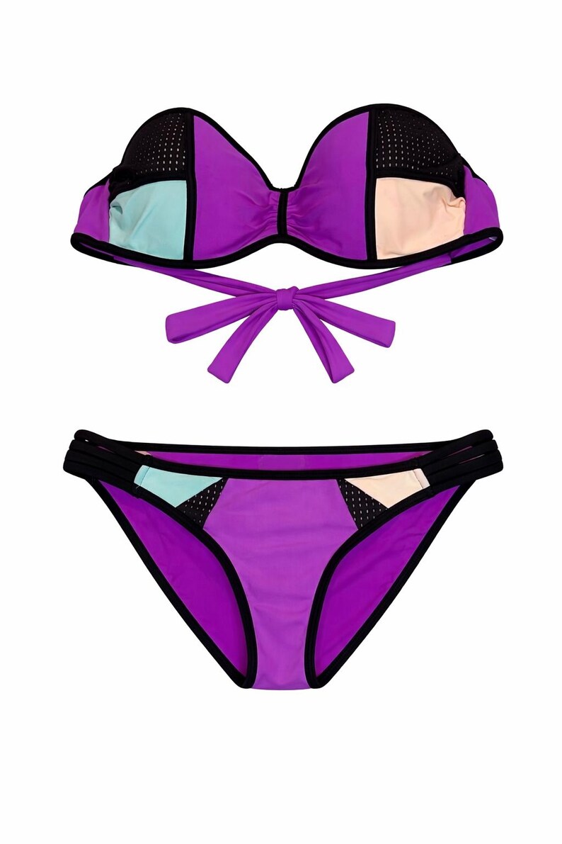 May include: A two-piece swimsuit in a vibrant colour block design. The bikini top features a bow tie closure and the bottoms have a classic cut. The colour scheme includes purple, black, light blue, and beige.