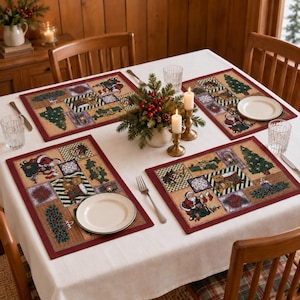Könnte beinhalten: Vier rechteckige Platzsets mit Patchwork-Design, das Weihnachtsmotive wie den Weihnachtsmann, Teddybären, Tannenbäume und Weihnachtssterne zeigt, alle mit dunkelrotem Rand, arrangiert auf einer weißen Tischdecke mit Tellern und Besteck.