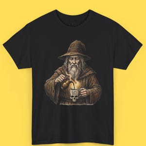 May include: Black t-shirt featuring a wizard pouring coffee into a skull-shaped mug. The wizard is wearing a brown robe and hat. The mug reads "MY DAILY DOSES OF DESPAIR".