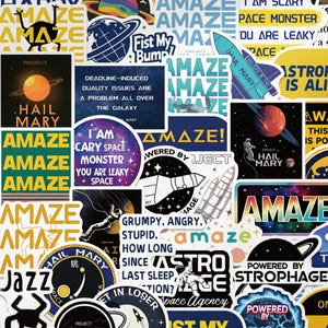 Könnte beinhalten: Eine Sammlung bunter Aufkleber mit Weltraum- und Science-Fiction-Themen. Designs umfassen Raketen, Planeten, Astronauten und Sätze wie "Amaze" und "Hail Mary."