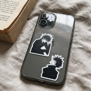 May include: A clear smartphone case featuring two black and white anime-style stickers of a character with spiky hair. The top sticker shows the character sitting with a hand on their chin, while the bottom sticker shows a profile view of the character.