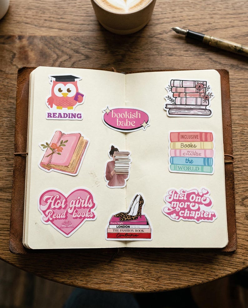 May include: An open notebook with various stickers featuring book-related themes. Stickers include an owl with a graduation cap, stacks of books, and phrases like "Hot girls Read books" and "Just one more chapter."