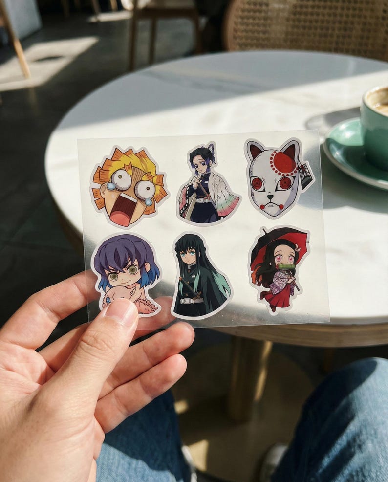 May include: A sheet of anime-style stickers featuring various characters. The stickers showcase vibrant colours and detailed illustrations of characters with distinct facial expressions and attire. The stickers are on a clear backing.