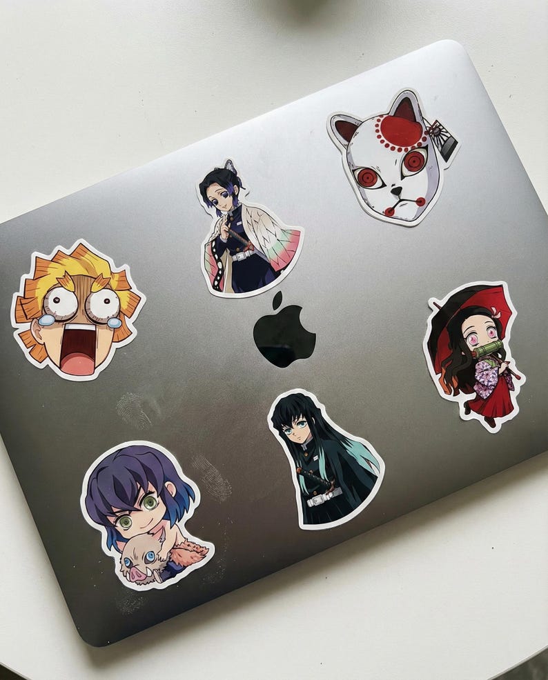 May include: A selection of anime character stickers, each with a unique design. The stickers display colourful illustrations of anime figures, including a character with yellow hair and wide eyes, and a character wearing a white mask with red accents.