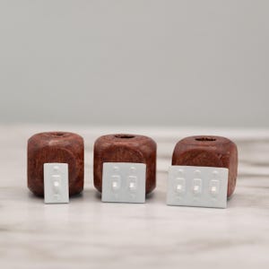 以下が含まれることがあります： 濃い茶色の木製ブロックが3つあり、それぞれに薄い灰色のミニチュアのライトスイッチが組み合わされています。スイッチにはそれぞれ1つ、2つ、3つのトグルスイッチがあります。ブロックは正方形で、上部に穴があります。