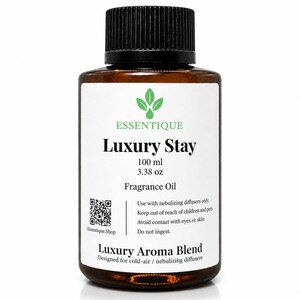 Könnte beinhalten: Eine braune Glasflasche "Luxury Stay" Duftöl mit schwarzem Deckel. Das Etikett enthält die Marke "Essentique", Produktdetails und Gebrauchsanweisungen. Die Flasche enthält 100 ml Öl.