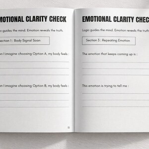 May include: Open notebook with the title "EMOTIONAL CLARITY CHECK" and prompts for self-reflection. The pages are white with black text, including sections for body signal scans and repeating emotions. The notebook is open on a white surface.