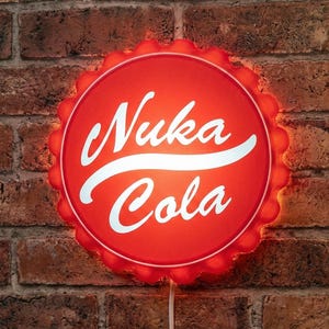 May include: A red, illuminated Nuka Cola bottle cap sign. The sign features the words "Nuka Cola" in white script. The sign is mounted on a brick wall and has a white power cord.