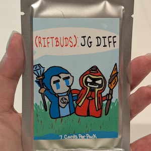 Peut inclure: Un paquet argenté scellé contenant un paquet de cartes à collectionner. Le paquet de cartes présente des illustrations de dessins animés de deux personnages, un en bleu et un en rouge, avec le texte "(RIFTBUDS): JG DIFF" et "7 cartes par paquet".