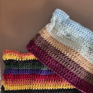 May include: Two crocheted striped blankets, one in a rainbow color scheme and the other in shades of brown, beige, and blue.