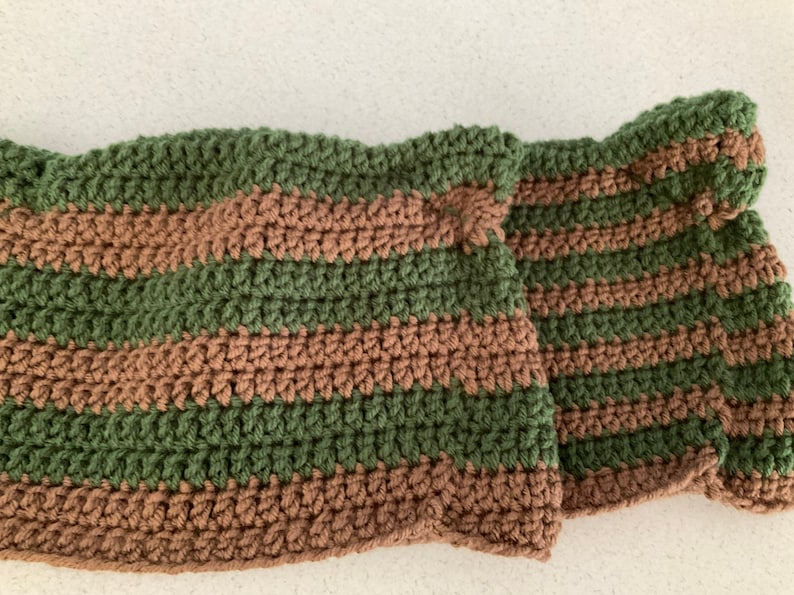 May include: A striped crocheted scarf in green and brown.