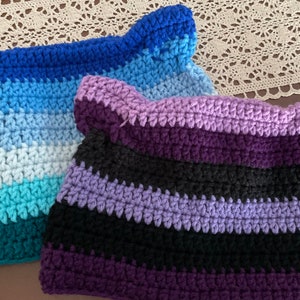 May include: Two crocheted hats with stripes in different color combinations. One hat is blue, teal, and white, and the other is purple, black, and lavender.