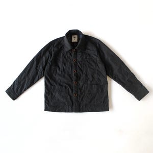 May include: A black long-sleeve jacket with a collared neckline and a button-down front. The jacket features two large patch pockets on the lower front, one chest pocket, and a visible brand label on the inner collar with a small tree graphic.