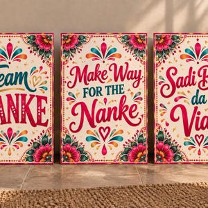 Op de afbeelding: Drie rechthoekige wandborden met een crèmekleurige achtergrond, voorzien van levendige bloemmotieven in roze, talingblauw en goud. De borden tonen de tekst Team NANKE, Make Way FOR THE Nanke en Sadi Bhen da Viah in decoratieve, kleurrijke typografie.