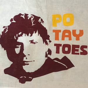 May include: A white fabric tote bag with a maroon silhouette of a person's head and shoulders. The text "PO TAY TOES!" is printed in yellow, orange, and maroon.
