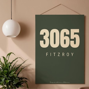 May include: A dark green wall art print with the numbers "3065" in a cream color, and the word "FITZROY" below. The text "Designed with love in Melbourne" is at the bottom. The print is hanging on a wall.