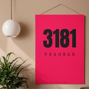 May include: A vibrant pink wall art print featuring the bold black numbers "3181" above the word "PRAHRAN". The print is suspended by a thin, light-colored string. The bottom right corner has the text "Designed with love... melbourne".