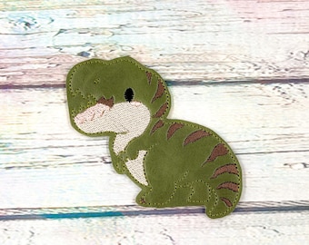 May include: A green dinosaur patch with brown stripes and a white belly. The patch is made of a textured material and has a stitched outline. The dinosaur is in a sitting position.