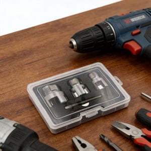 May include: A clear plastic case containing several silver drill bit adapters and a small tool. A blue and black cordless drill is in the background, along with other tools like pliers and a screwdriver. The items are on a wooden surface.