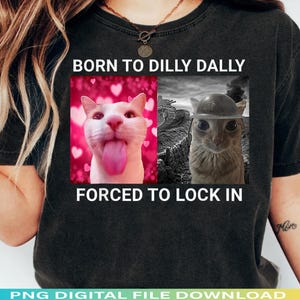 May include: Black t-shirt with the text "BORN TO DILLY DALLY FORCED TO LOCK IN". The shirt features two images of cats, one with a pink background and the other in black and white.