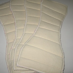 May include: Four white quilted fabric inserts for cloth diapers. The inserts have a white binding around the edges.