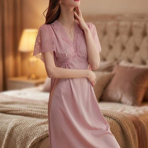 May include: A dusty rose-colored nightgown with lace detailing. The V-neckline and short sleeves are trimmed with delicate lace. The nightgown is made of a soft, flowing fabric, creating a romantic and elegant look.
