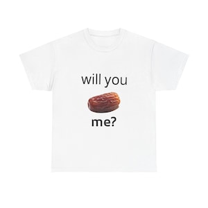 Peut inclure: T-shirt blanc avec l'inscription "will you" au-dessus d'une datte et "me?" en dessous. La datte est marron et de forme ovale. Le t-shirt est de style décontracté.