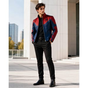 Op de afbeelding: Een rode, blauwe en zwarte leren jas met een opstaande kraag. De jas heeft een ontwerp op de borst en mouwen. De persoon draagt een zwart shirt, een zwarte broek en zwarte laarzen.