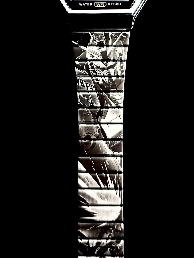 May include: Black and white digital watch with a detailed illustration of a robot on the watch band. The watch face displays the text "WATER WR RESIST". The watch band is segmented with a repeating design.
