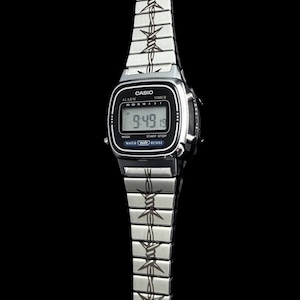 May include: A silver Casio digital watch with a black face displaying the time 9:49. The watch band features a barbed wire design. The watch has alarm, timer, mode, start-stop, water resist functions.