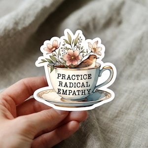 May include: A sticker featuring a teacup filled with flowers and a bird. The teacup has the words "PRACTICE RADICAL EMPATHY" printed on it. The teacup is on a saucer, and the design has a watercolor style.
